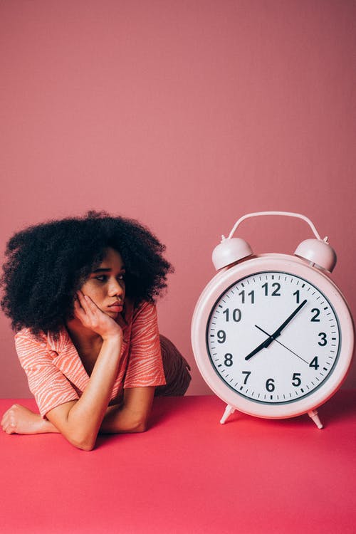 Woman Looking at a Big Pink Alarm Clock