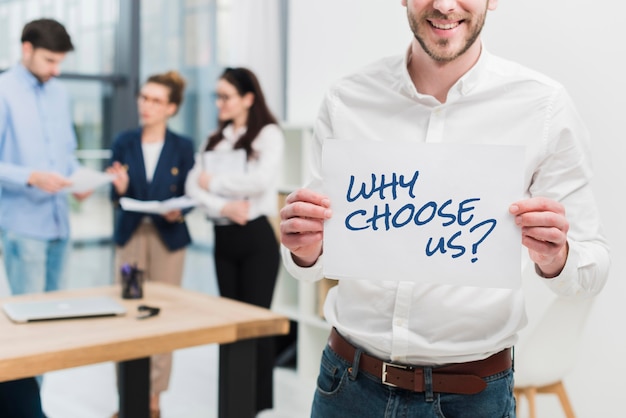 Free photo business man holding a paper with the why choose us question