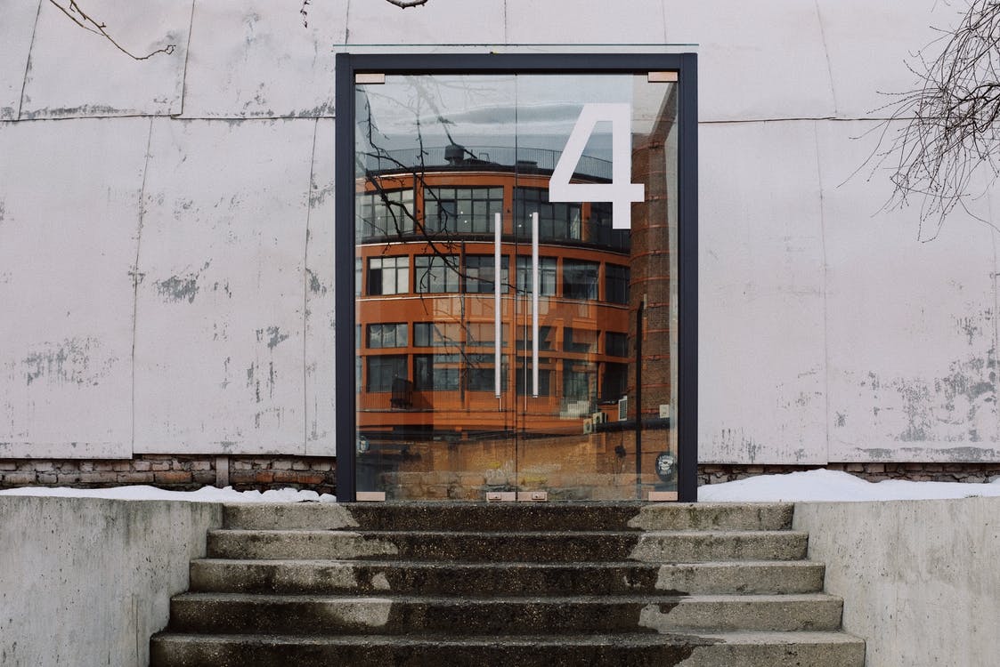 From below of modern building facade with number four on glass entrance door and stairs