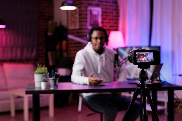 Free photo young man filming podcast episode on camera in studio, live broadcasting online discussion to create social media content. male influencer vlogging show with livestream equipment.